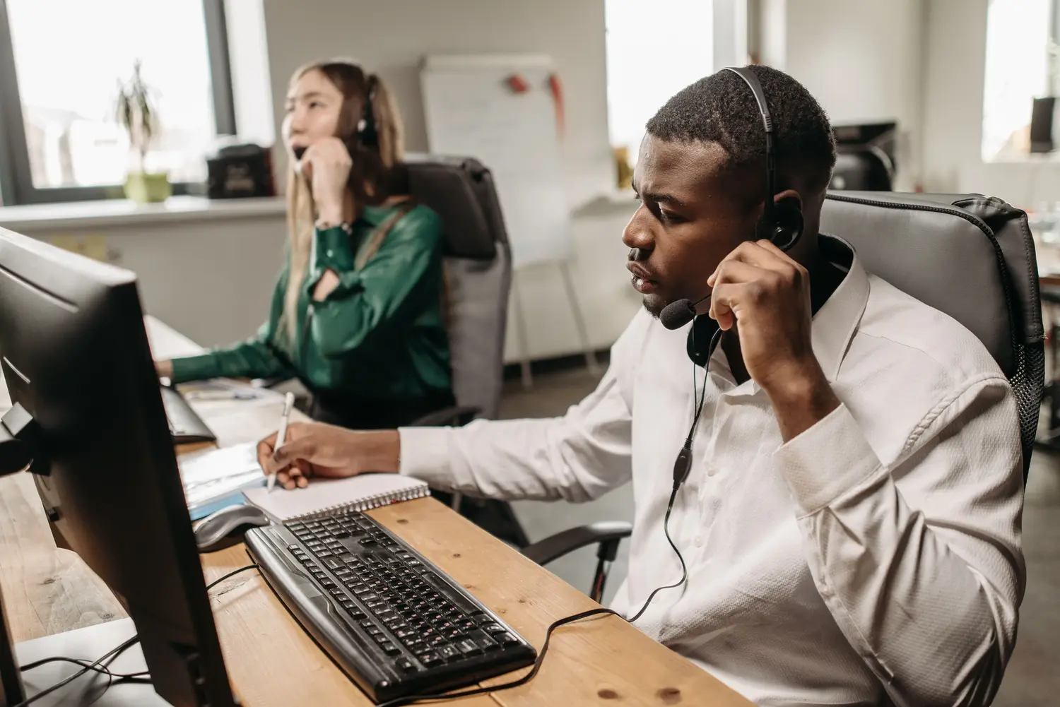 Man wearing headset, smiling, working on laptop